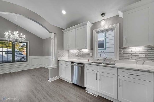 kitchen featuring pendant lighting, lofted ceiling, sink, stainless steel dishwasher, and white cabinetry