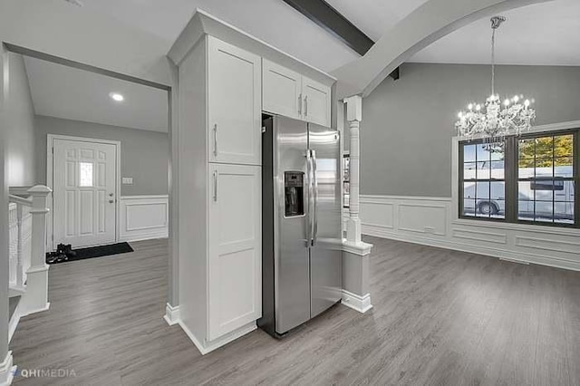 kitchen featuring white cabinets, stainless steel fridge, vaulted ceiling with beams, and light hardwood / wood-style flooring