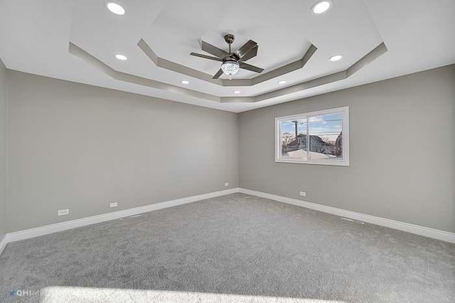 carpeted spare room featuring ceiling fan and a tray ceiling