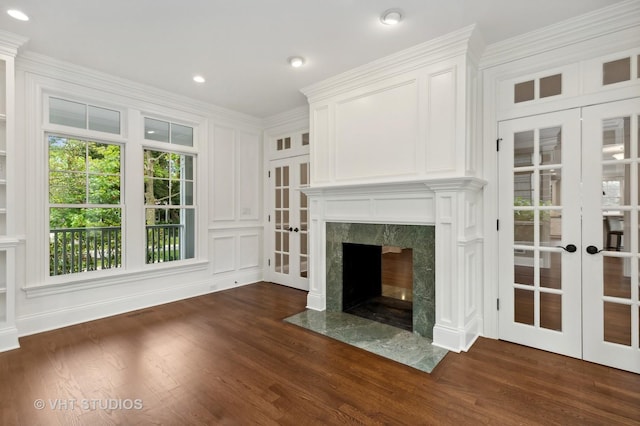 unfurnished living room with french doors, dark wood-type flooring, a premium fireplace, and crown molding