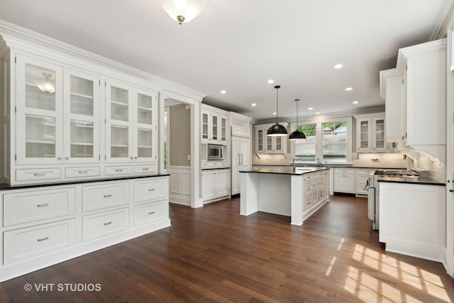 kitchen with white cabinets, gas range gas stove, a kitchen island, tasteful backsplash, and hanging light fixtures