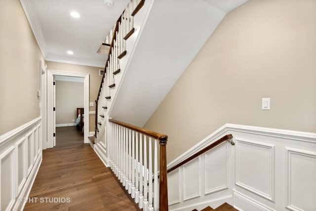 staircase with wood-type flooring and crown molding