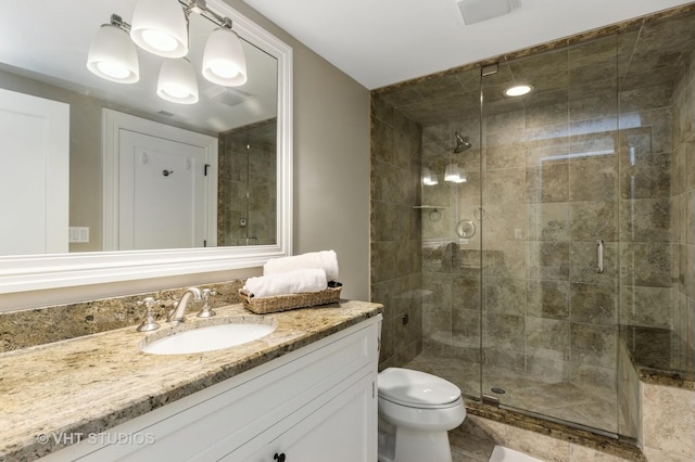 bathroom with a shower with shower door, toilet, and vanity