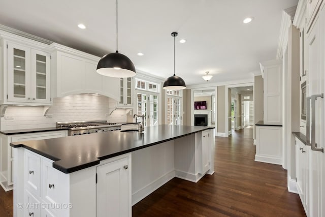 kitchen with stove, sink, white cabinets, and decorative light fixtures