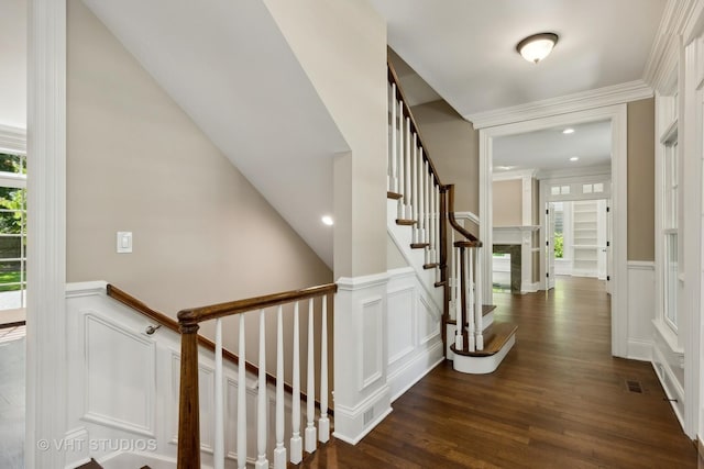 stairway with a high end fireplace, a wealth of natural light, crown molding, and hardwood / wood-style flooring