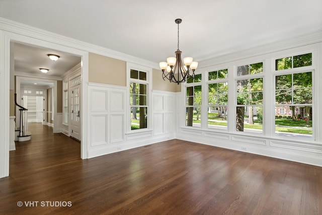 unfurnished dining area with an inviting chandelier, dark hardwood / wood-style flooring, and ornamental molding