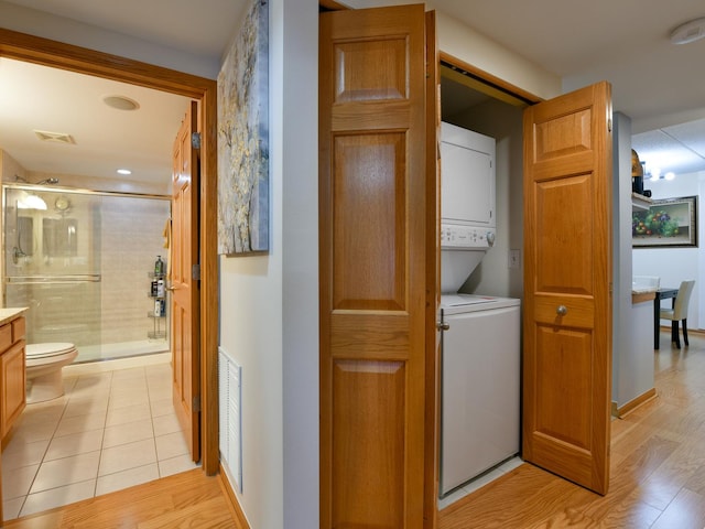 washroom with stacked washer and dryer and light hardwood / wood-style floors