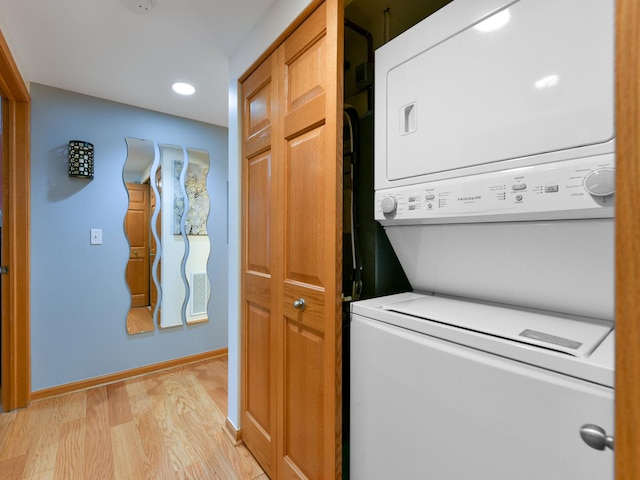 laundry room featuring light hardwood / wood-style flooring and stacked washing maching and dryer