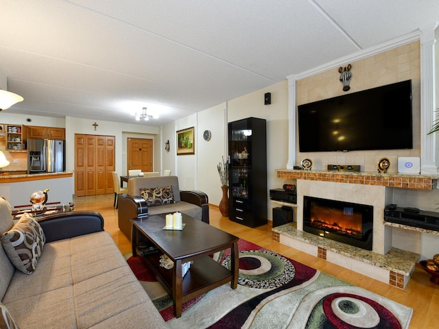 living room with a tile fireplace and light hardwood / wood-style floors