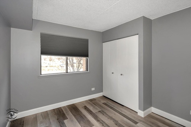 unfurnished bedroom featuring a closet, a textured ceiling, and light hardwood / wood-style flooring