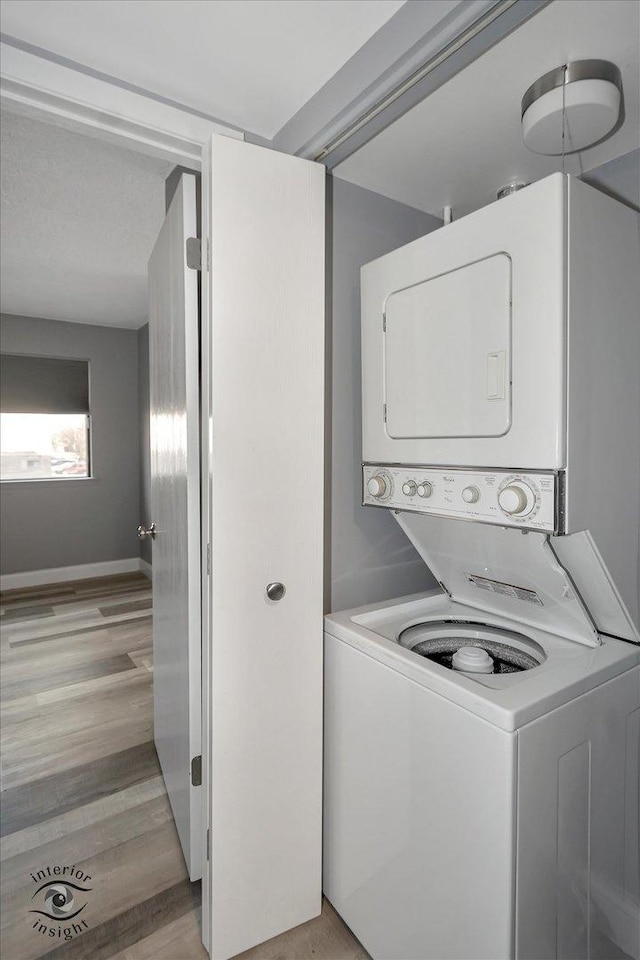 laundry room featuring light hardwood / wood-style floors and stacked washing maching and dryer