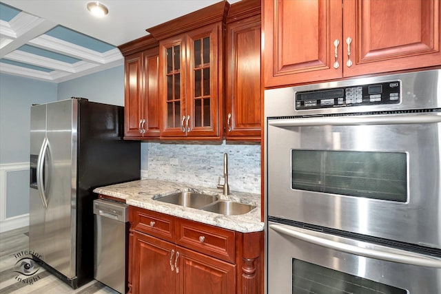 kitchen featuring coffered ceiling, sink, appliances with stainless steel finishes, beam ceiling, and light stone counters