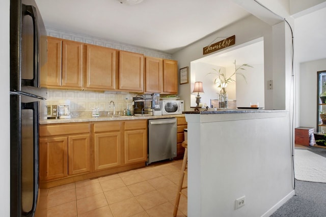 kitchen with black refrigerator, decorative backsplash, sink, dishwasher, and light tile patterned flooring