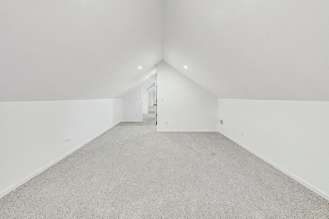 bonus room with light colored carpet and vaulted ceiling