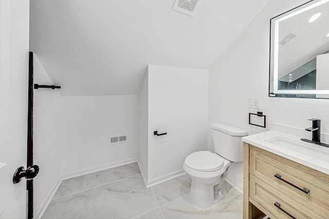 bathroom featuring toilet, vanity, and vaulted ceiling