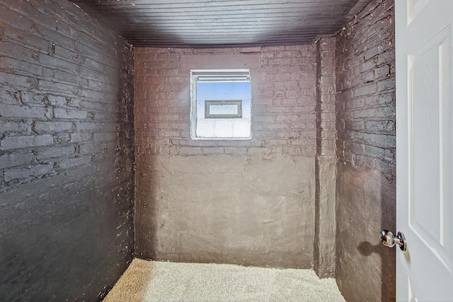 interior space featuring wooden ceiling and brick wall