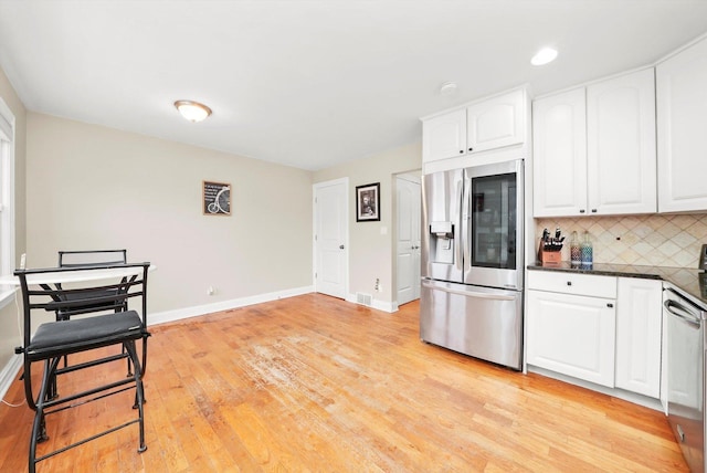 kitchen featuring light hardwood / wood-style floors, white cabinetry, appliances with stainless steel finishes, and tasteful backsplash