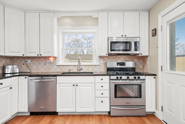 kitchen with light wood-type flooring, stainless steel appliances, white cabinetry, and sink