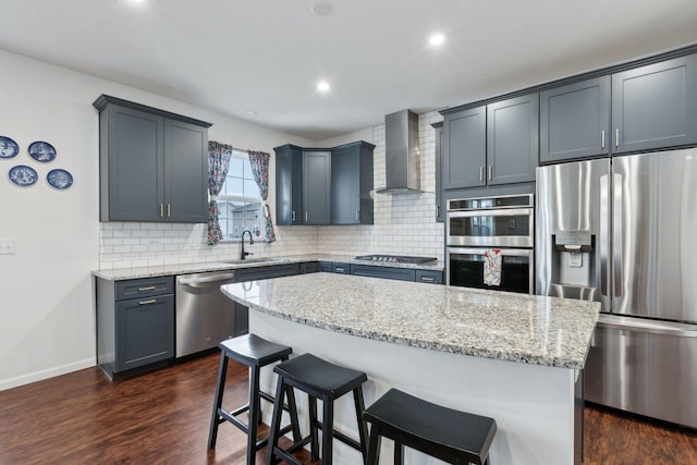 kitchen featuring a center island, dark wood-type flooring, wall chimney exhaust hood, tasteful backsplash, and stainless steel appliances