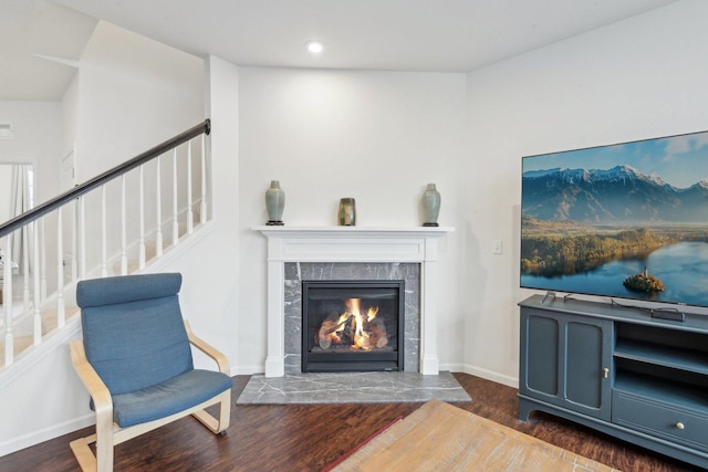 living area with dark hardwood / wood-style flooring and a tiled fireplace