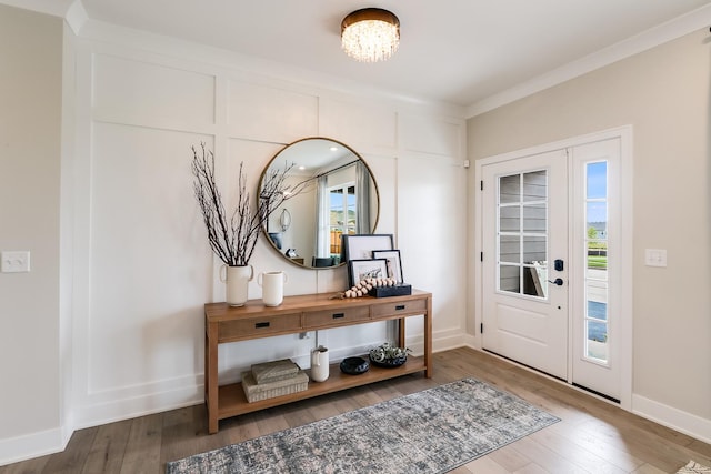 foyer with hardwood / wood-style floors, an inviting chandelier, and crown molding