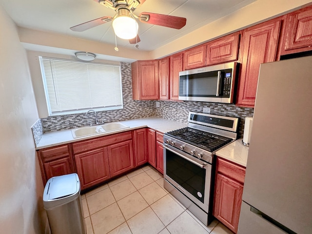 kitchen featuring appliances with stainless steel finishes, backsplash, ceiling fan, sink, and light tile patterned floors