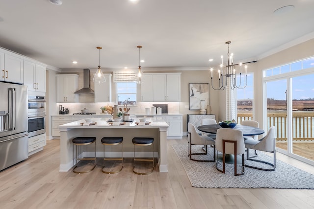 kitchen featuring decorative backsplash, stainless steel appliances, wall chimney range hood, pendant lighting, and a kitchen island