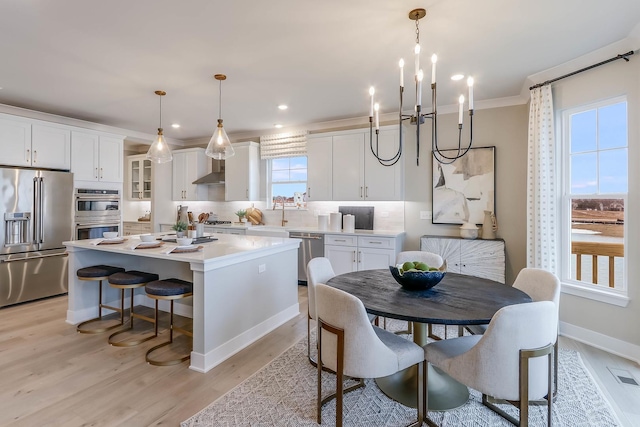 dining space with a notable chandelier, crown molding, and light hardwood / wood-style flooring