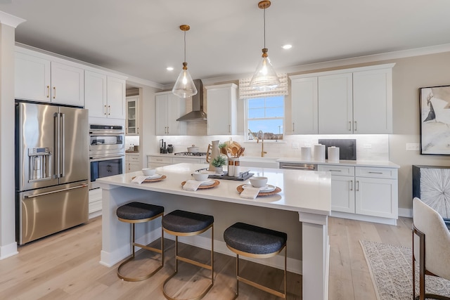 kitchen with white cabinets, stainless steel appliances, and wall chimney exhaust hood