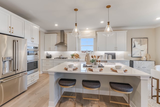 kitchen with a center island, wall chimney exhaust hood, stainless steel appliances, tasteful backsplash, and white cabinets