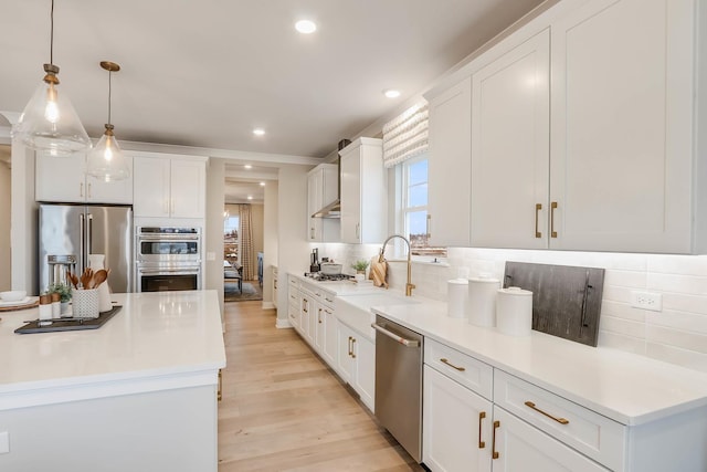 kitchen featuring white cabinetry, sink, hanging light fixtures, and appliances with stainless steel finishes