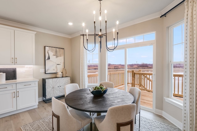 dining space featuring light hardwood / wood-style floors, an inviting chandelier, and crown molding