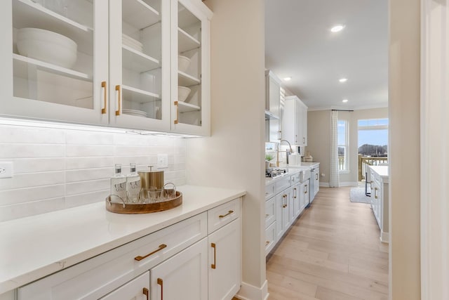 kitchen featuring white cabinets, light hardwood / wood-style floors, backsplash, and stainless steel gas cooktop