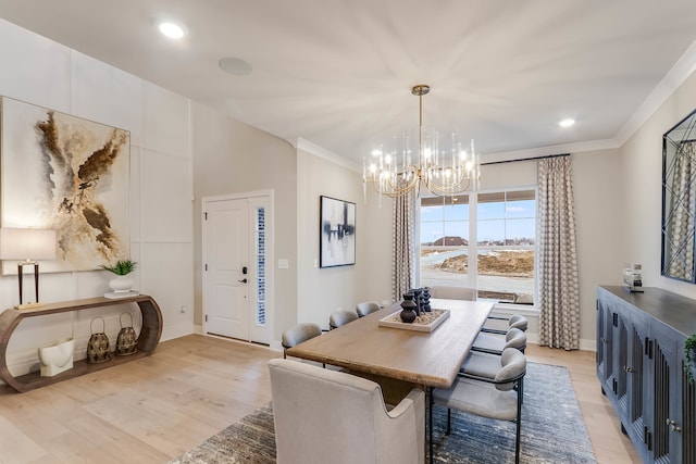 dining area with ornamental molding, light wood-type flooring, and a notable chandelier