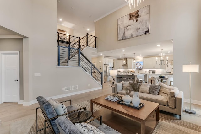 living room with crown molding, light hardwood / wood-style flooring, and an inviting chandelier