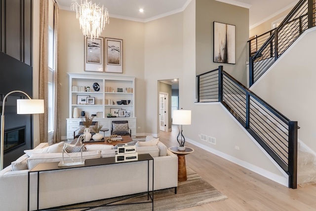 living room featuring a wealth of natural light, light hardwood / wood-style flooring, an inviting chandelier, and ornamental molding