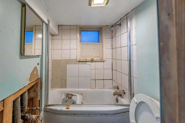 bathroom with toilet and tiled shower / bath