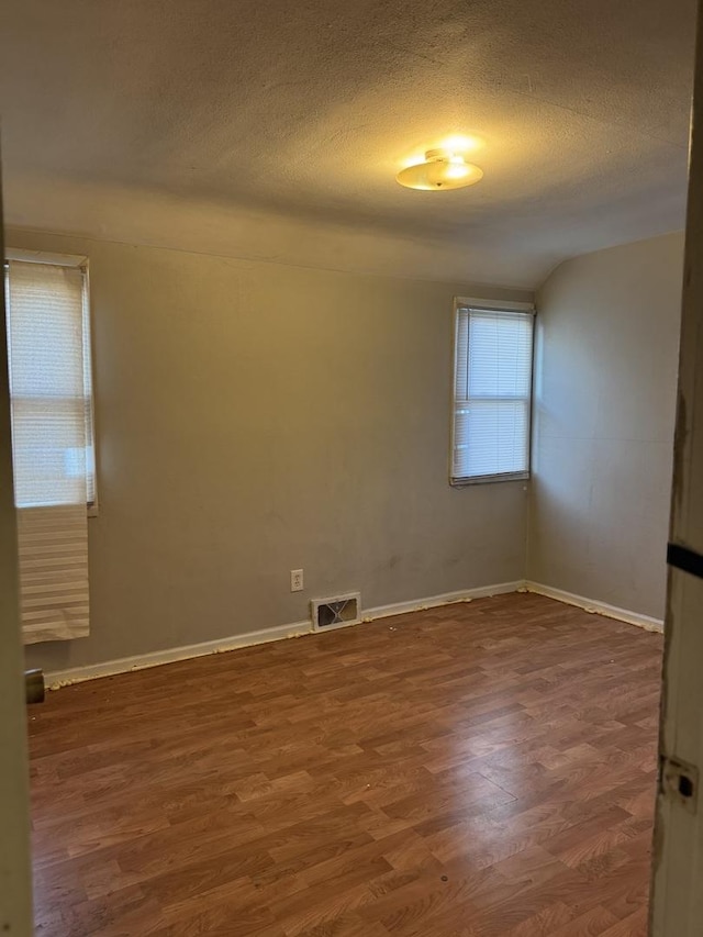 empty room with a textured ceiling and dark hardwood / wood-style flooring