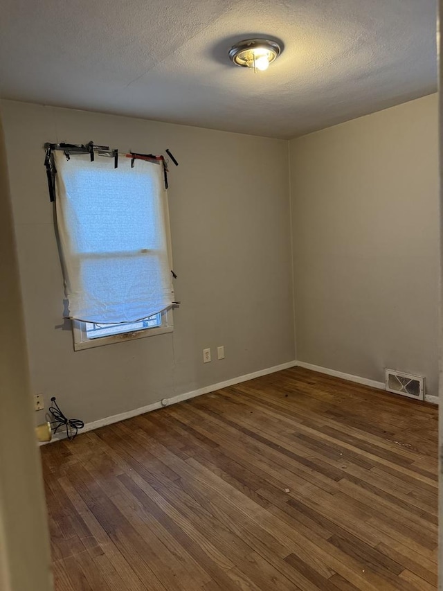 unfurnished room with hardwood / wood-style floors and a textured ceiling