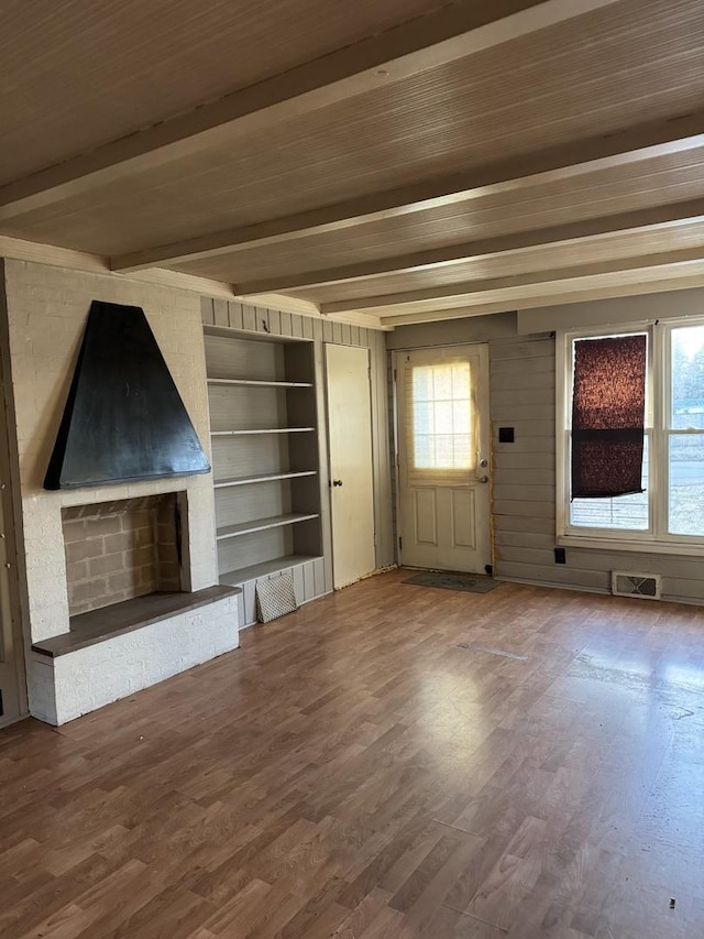 unfurnished living room featuring hardwood / wood-style flooring, beam ceiling, built in features, and a wealth of natural light