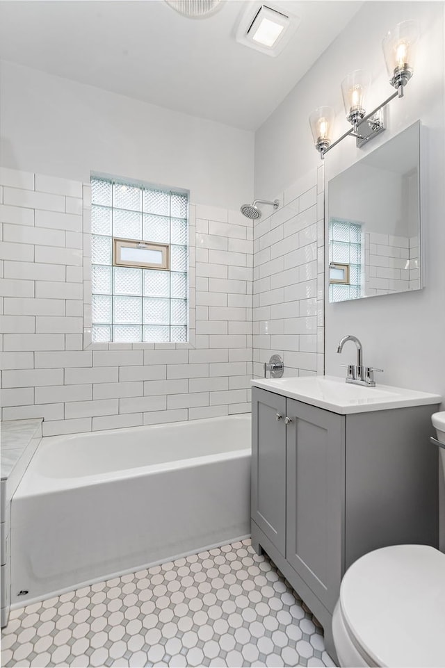 full bathroom with vanity, tiled shower / bath combo, and toilet