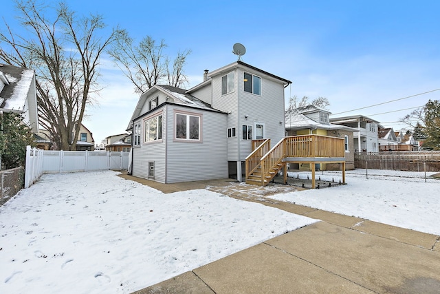 snow covered rear of property featuring a deck