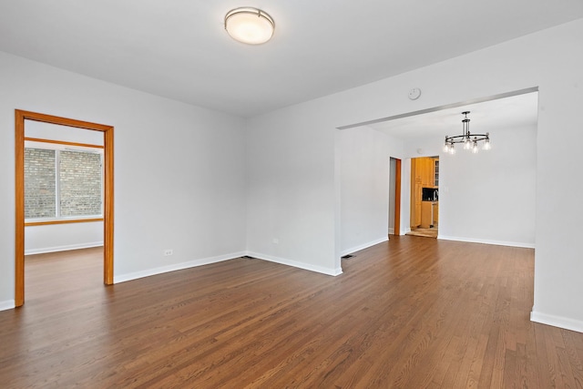 spare room featuring dark hardwood / wood-style flooring and a chandelier