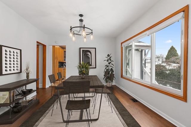 dining space featuring sink, a chandelier, and hardwood / wood-style flooring