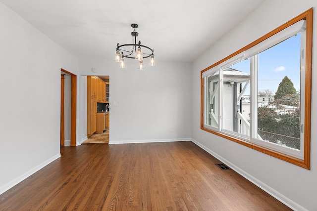 unfurnished room featuring a chandelier, hardwood / wood-style flooring, and a wealth of natural light