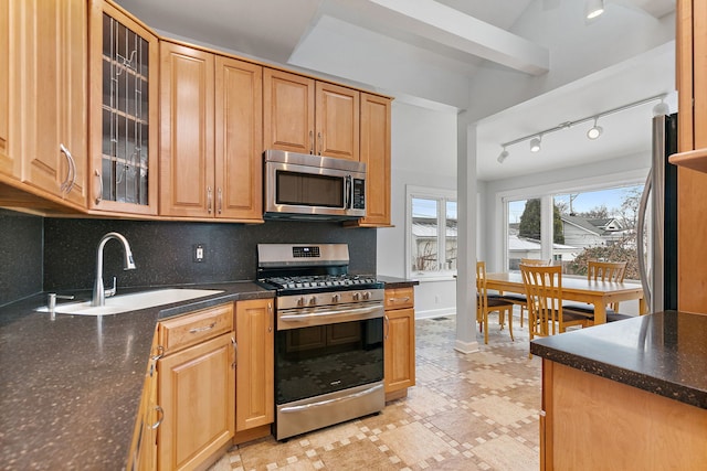 kitchen featuring decorative backsplash, appliances with stainless steel finishes, dark stone counters, and sink