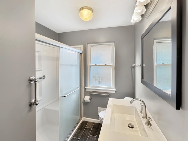 bathroom featuring toilet, an enclosed shower, sink, and a wealth of natural light