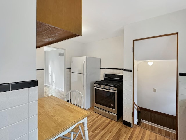 kitchen with white refrigerator, light hardwood / wood-style floors, and stainless steel range