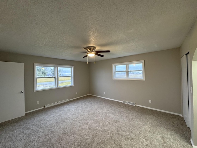 carpeted empty room with ceiling fan, a textured ceiling, and a baseboard heating unit