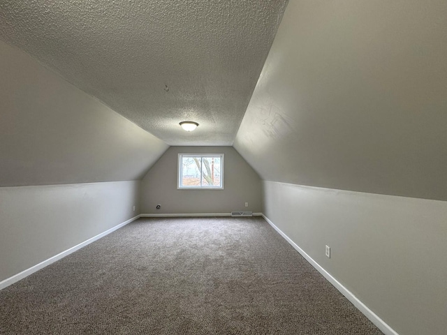 bonus room featuring carpet, lofted ceiling, and a textured ceiling